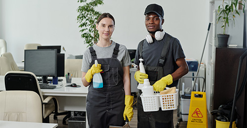 two young intercultural cleaning service company workers coveralls gloves